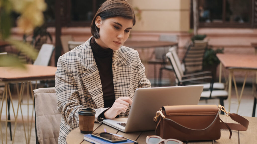 Mujer planificando un viaje internacional desde su laptop en una cafetería